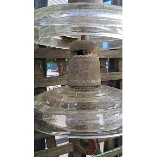 232 - A group of three overhead power-line glass disc insulators, each fitted with a metal cap and hook su... 