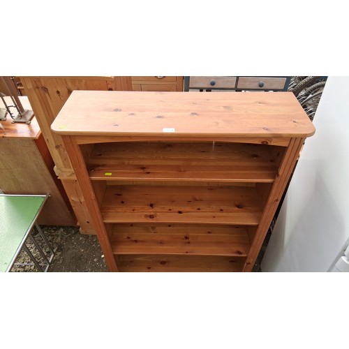 249A - Pine open bookcase, raised on a plinth base with bun feet.