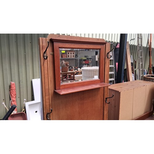 250A - Early 20th century oak hall stand with iron coat hooks, over a divided drawer and cupboard.