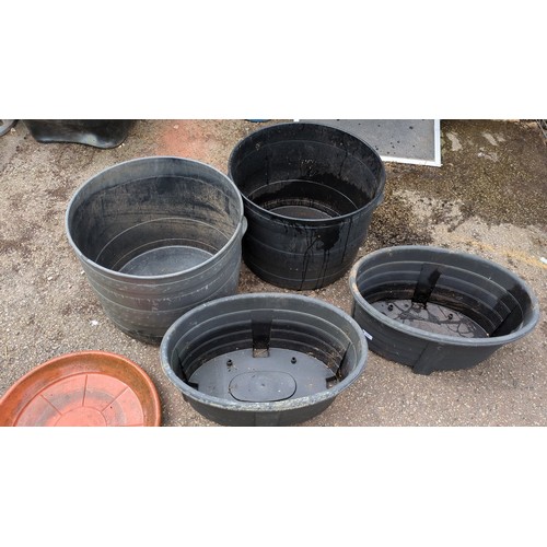 98 - A group of plastic garden planters comprising two large cylindrical tubs and two oval trough planter... 