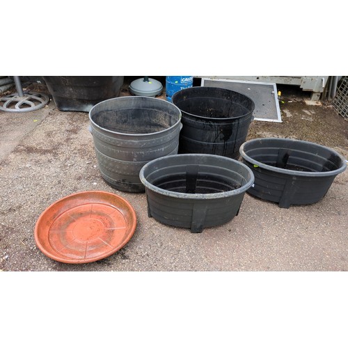 98 - A group of plastic garden planters comprising two large cylindrical tubs and two oval trough planter... 