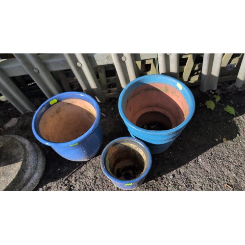 59e - A set of three glazed terracotta planters, including two cylindrical pots and a stepped, banded plan... 