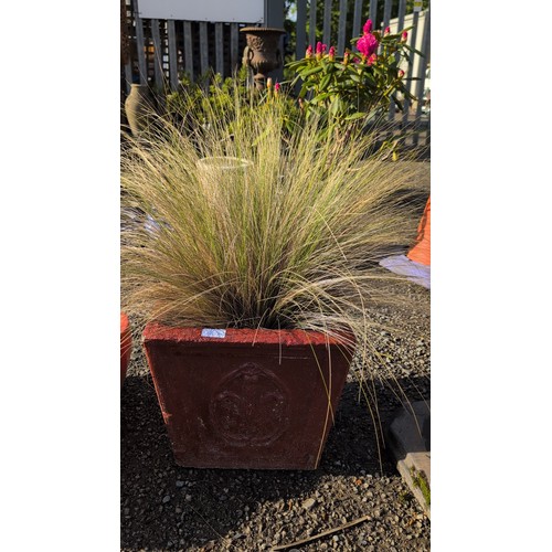 90a - Concrete garden planter, painted red, the sides with a raised circular wreath medallion; planted wit... 