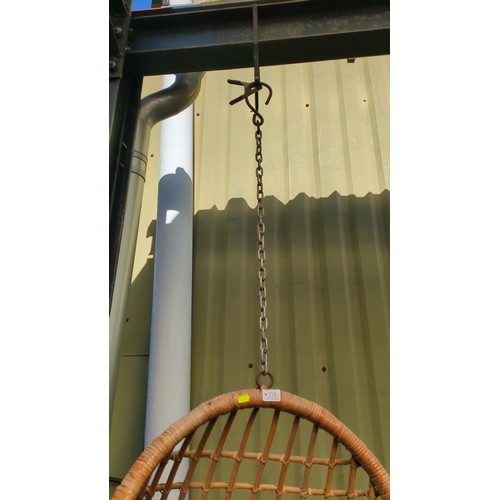 Rattan hanging egg chair suspended by a metal chain.