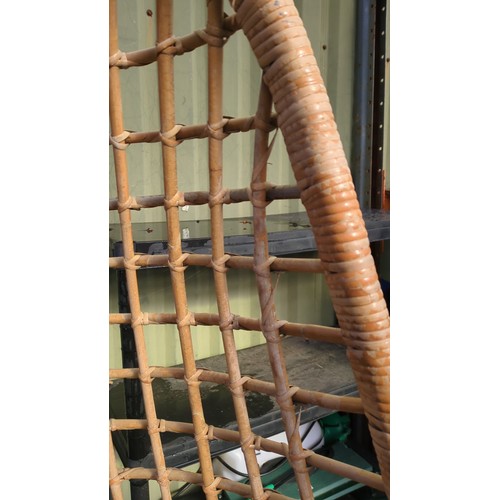 Rattan hanging egg chair suspended by a metal chain.