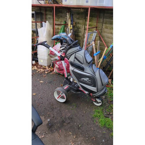 Lot 359: Motocaddy M1 electric golf trolley with 28V lithium battery, carrying a PowaKaddy Premium Edition cart bag and assorted clubs, including Ping G woods, irons and an Odyssey putter.