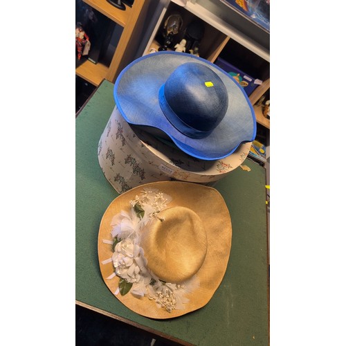 Three wide-brimmed woven hats in navy, turquoise and ochre; the ochre ...