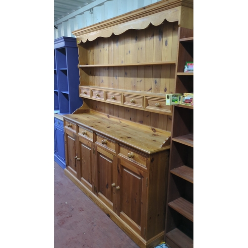Lot 513B: Pine kitchen dresser with moulded cornice and shaped apron above open shelving and five small drawers; the lower section with four drawers over four panelled cupboard doors, fitted with turned wooden knobs.