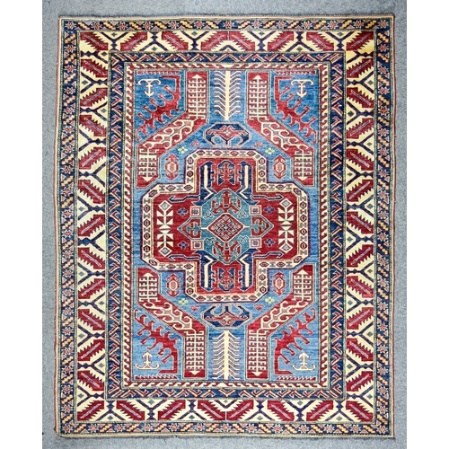 151 - An Early 20th Century Caucasian Rug woven in colours of ivory, blue and wine, with a bold stylised c... 