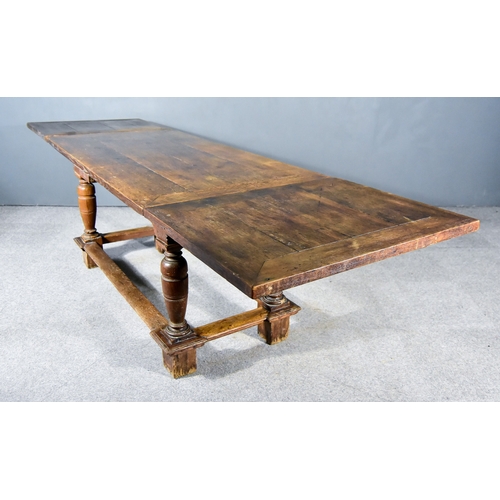 257 - An Old Oak Continental Draw Leaf Extending Dining Table, with four plank cleated top, carved frieze ... 