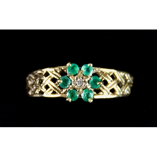 600 - A 9ct Gold Emerald and Diamond Flower Head Ring, set with six small emeralds and one small diamond i... 