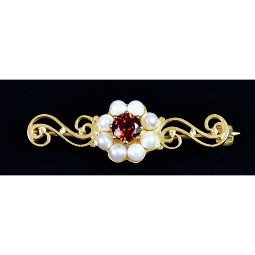 624 - A 9ct Gold Bar Brooch, set with a centre faceted garnet surrounded by small seed pearls, 35mm in len... 
