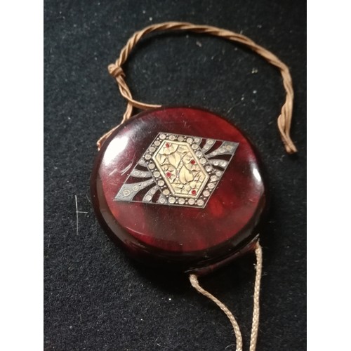 126 - 1920's plastic compact with fabric tassel and chinese style design to front 2½