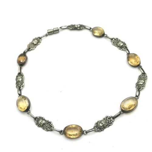 177 - Silver necklace alternating with yellow stones & oriental mask themed panels (has a white metal clas... 