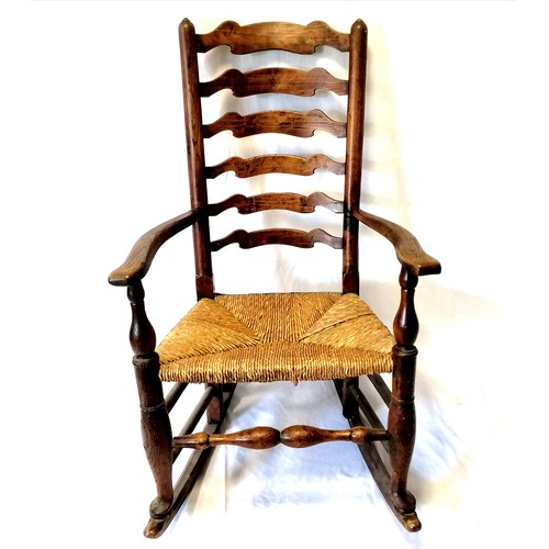 609 - Oak country ladder back rocking chair with a rush seat. In good condition