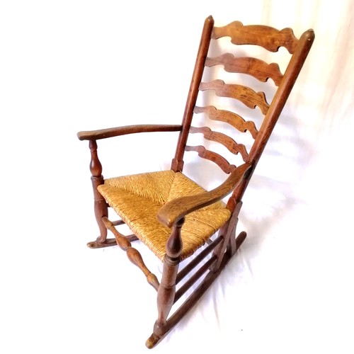 609 - Oak country ladder back rocking chair with a rush seat. In good condition