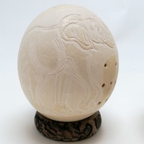 55 - 2 x ostrich eggs carved with rhino & elephant signed Musa - both have wooden stands