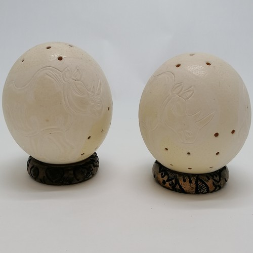 55 - 2 x ostrich eggs carved with rhino & elephant signed Musa - both have wooden stands