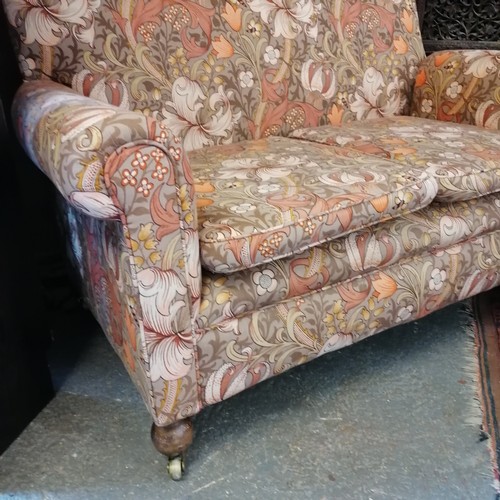 743 - Small two seater settee on bun feet with casters' with orange floral fabric 134cm wide x 80cm high x... 