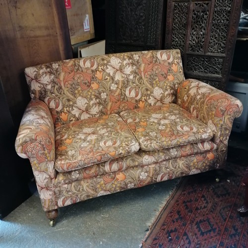 743 - Small two seater settee on bun feet with casters' with orange floral fabric 134cm wide x 80cm high x... 