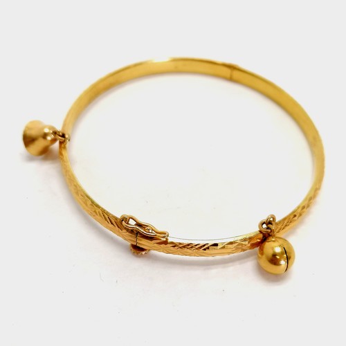 120 - Chinese gold marked high carat bangle decorated with 2 bells, screw down safety catch approx. 6cm di... 