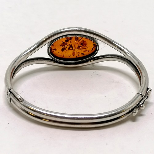 202 - Unmarked silver and amber bangle - 32.8g total weight & 7cm across