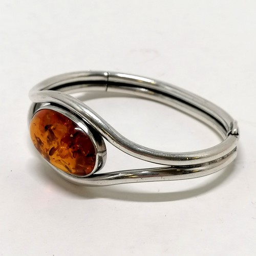 202 - Unmarked silver and amber bangle - 32.8g total weight & 7cm across