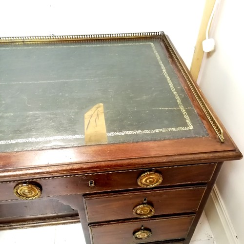 664 - Antique mahogany kneehole desk with green leather insert (has damage) and brass gallery. 127cm wide ... 