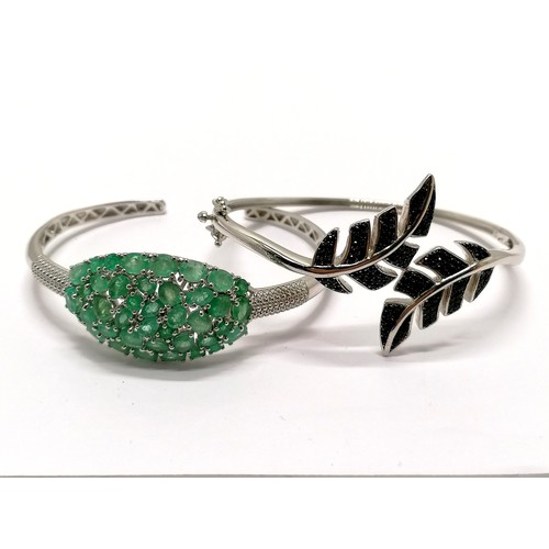 241 - 2 x silver stone set bangles - 1 is set with emeralds and has a sprung end & the other is black ston... 