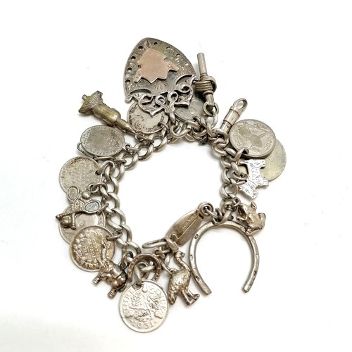 527 - Antique silver charm bracelet (with unusual catch - patent 610430) with assorted fobs, charms, coins... 