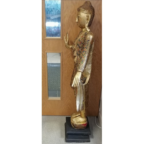 35 - Hand carved wooden standing Buddha figure with gilded decoration and coloured glass detail on an ebo... 