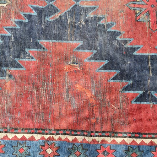 166 - Persian red ground rug with blue geometric central medallions, some repair and ,wear, 145 cm wide, 2... 