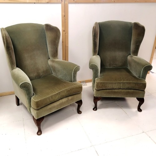 245 - Pair of wing back easy chairs, upholstered in a green plush material, 78 cm  wide, 100 cm high, 70 c... 