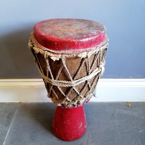 259 - African tribal red painted wooden drum with plaited string tensioners with woven cloth detail 56cm h... 