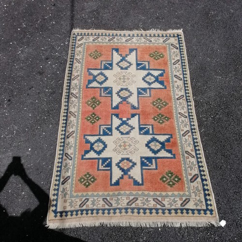 68 - Cream and pink ground eastern wool rug. 133cm x 217cm. In good used condition