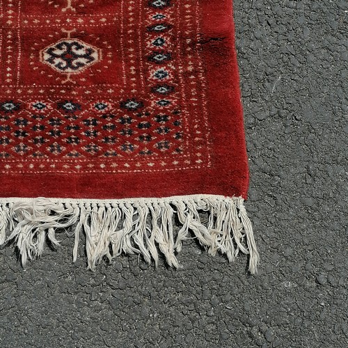 92 - Large Pakistani Bokhara late 20th century carpet in red. Measures 302 x 225cm. In good used conditio... 