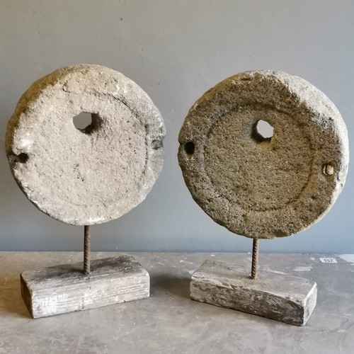 212 - Matched pair of sandstone mill stones mounted on a iron rod and driftwood bases, 32 cm wide, 11 cm d... 