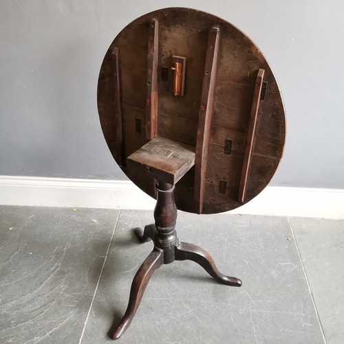 75 - Antique oak tilt top circular table on turned column terminating on tripod base, 73cm diameter x 68c... 