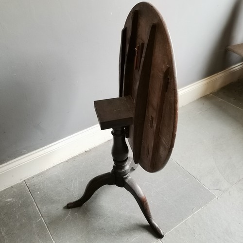 75 - Antique oak tilt top circular table on turned column terminating on tripod base, 73cm diameter x 68c... 