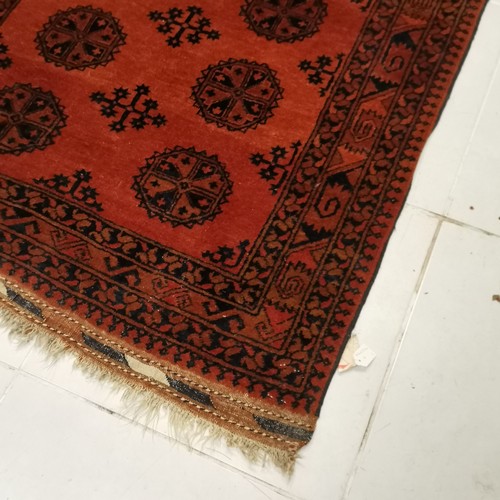 146 - Red ground rug with all over medallions within border and pattern to fringing, in good used conditio... 