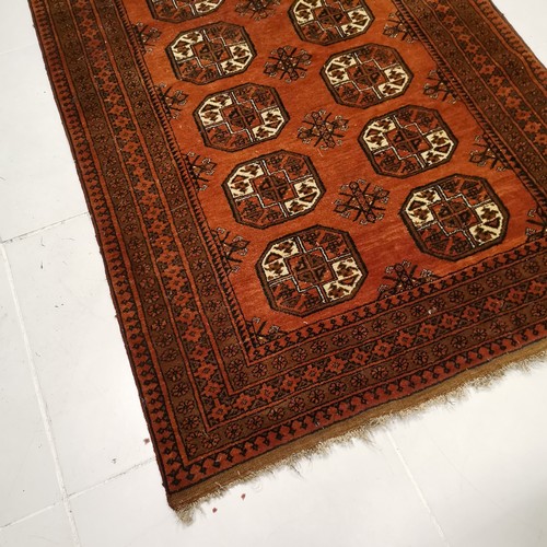 147 - Brown ground rug with medallions within wide border, in good condition, 125 cm wide x 195 cm .