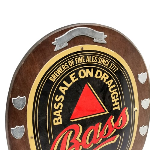 202 - Bass ale enamelled advertising sign mounted on a wooden shield - 57cm x 47cm