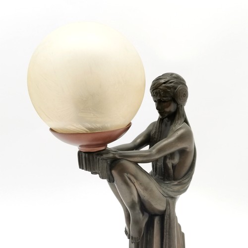 327 - Art deco style lamp of a seated figure holding a glass globe shade  45cm high