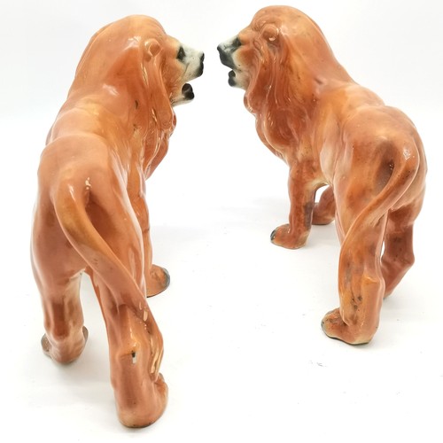 84 - Pair of antique Staffordshire standing lion figures 26cm high x 32cm long - 1 leg has an old repair ... 