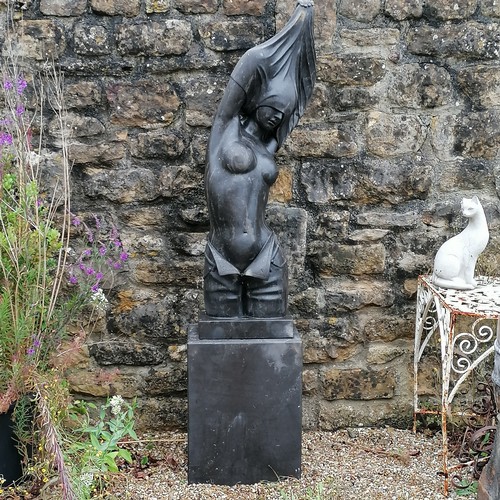 36 - Contemporary carved large black marble female semi-nude female figure on a rectangular matching base... 