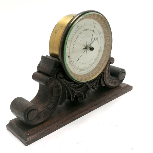 208 - Antique aneroid barometer with curved thermometer on hand carved oak stand - 21cm high x 32cm wide x... 