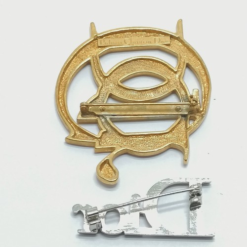 615 - Parfums Christian Dior gold tone logo brooch (6cm) t/w silver tone brooch