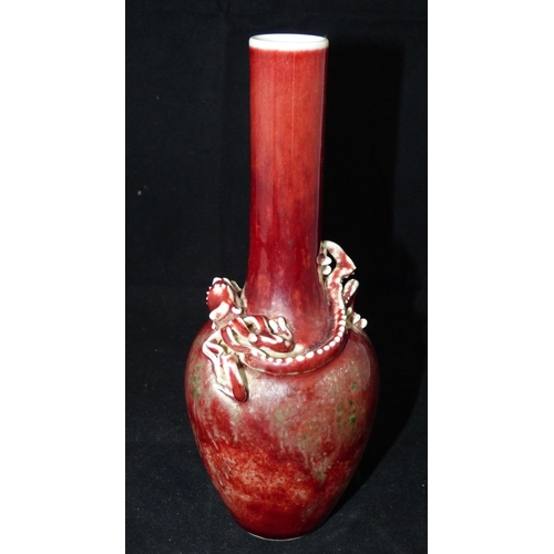 201 - An Oriental Bulbous Thin Neck Vase on red ground having raised dragon motif, 21.5cm high  