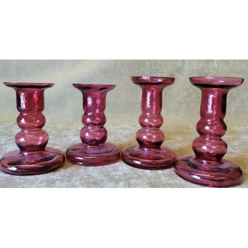 89 - A Pair of Ruby Glass Candlesticks on sweeping bases, 12cm high, also a smaller pair of Ruby glass ca... 