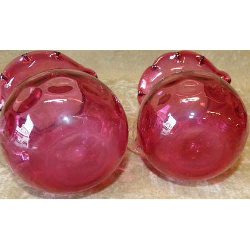 94 - 2 Cranberry Bulbous Shape Jugs having scalloped rims with clear reeded handles, 13cm high  